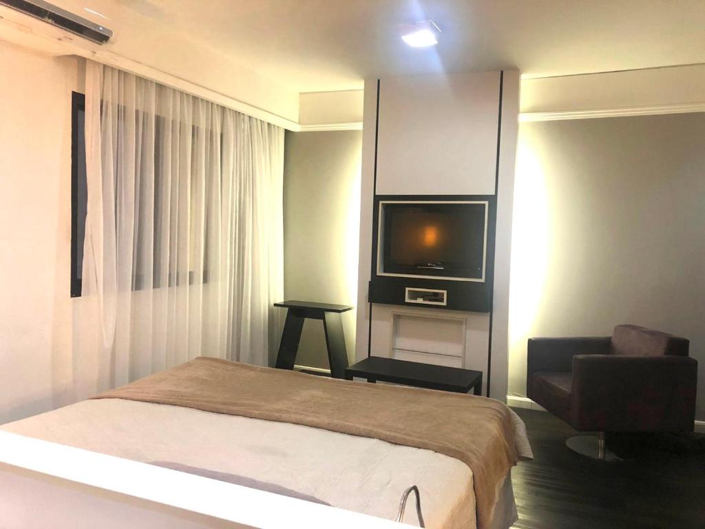 um quarto com uma cama, uma televisão e uma cadeira em Apto Privativo em Hotel de Luxo no Ibirapuera em São Paulo