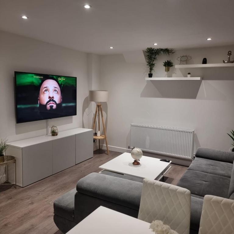 a living room with a couch and a flat screen tv at 4 bed apartment In Enfield north London in Enfield Lock