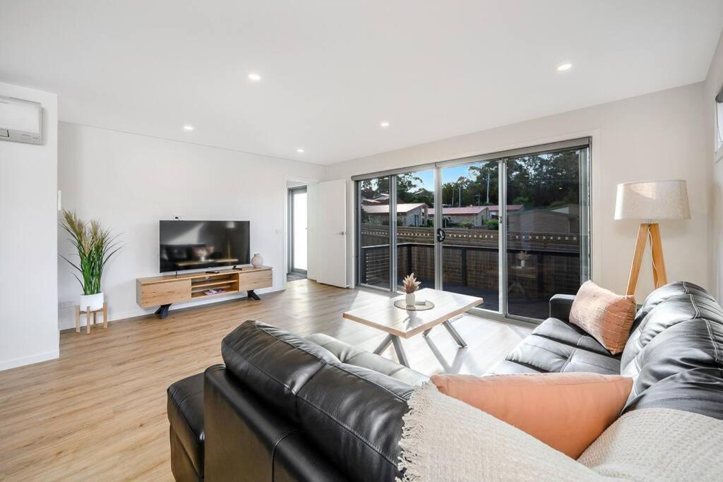 a living room with a black leather couch and a tv at The Bay Townhouse 500m to beach 15min to CBD in Hobart