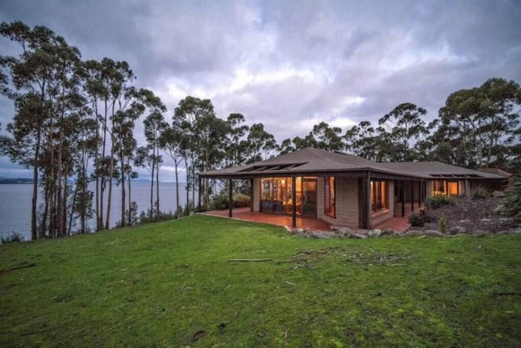 a small house on a hill with a green lawn at Tinderbox Cliff House - Waterside Private Retreat in Hobart