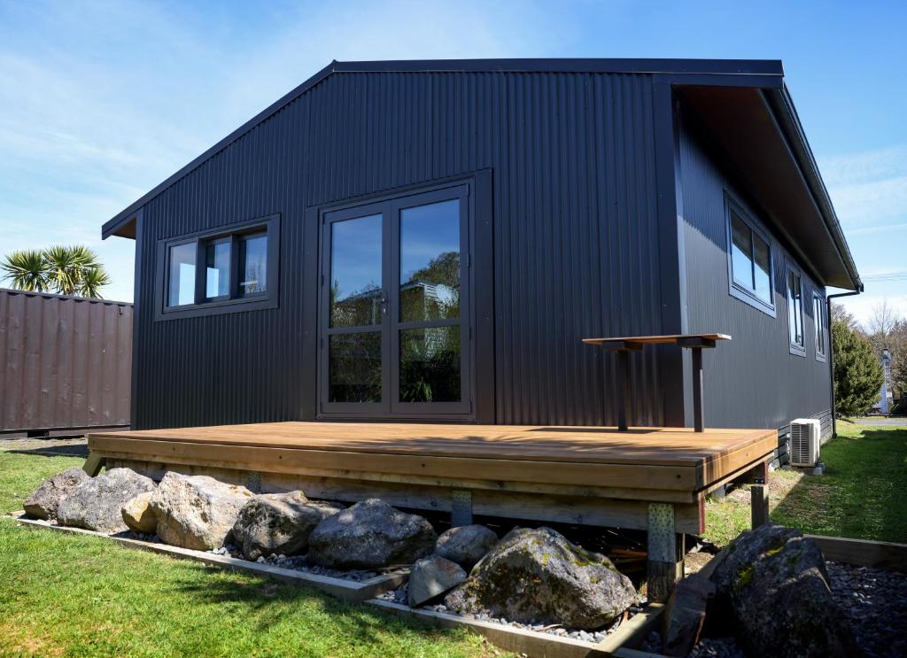 a black house with a wooden deck and some rocks at Scott Base - National Park Holiday Home in National Park
