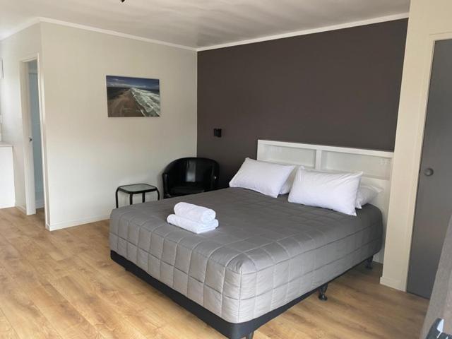 a bedroom with a bed with two white towels on it at Wayfarer Motel in Kaitaia