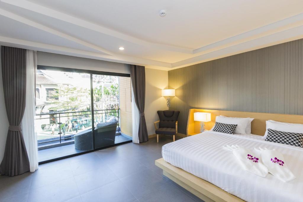 a bedroom with a large bed and a large window at The Capuchin Hotel Krabi, Ao Nang Beach - SHA Plus in Ao Nang Beach