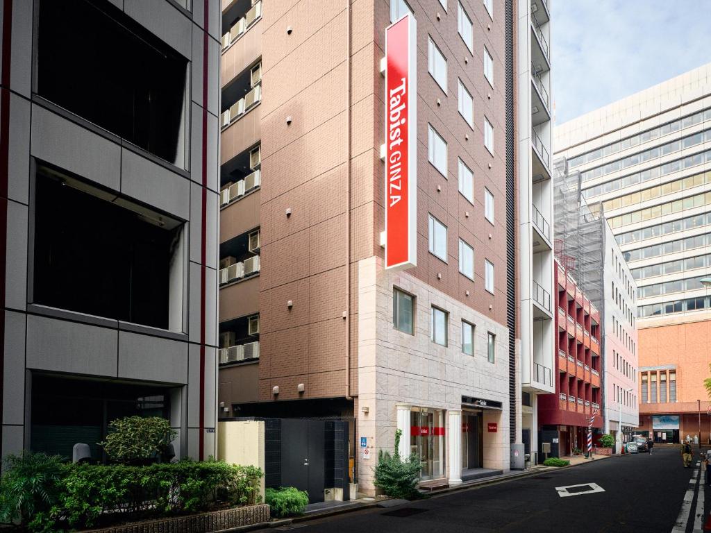 a building with a red sign on the side of it at Tabist Ginza in Tokyo