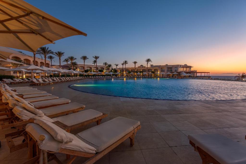 une piscine avec des chaises longues et un complexe hôtelier dans l'établissement Cleopatra Luxury Resort Sharm El Sheikh, à Charm el-Cheikh