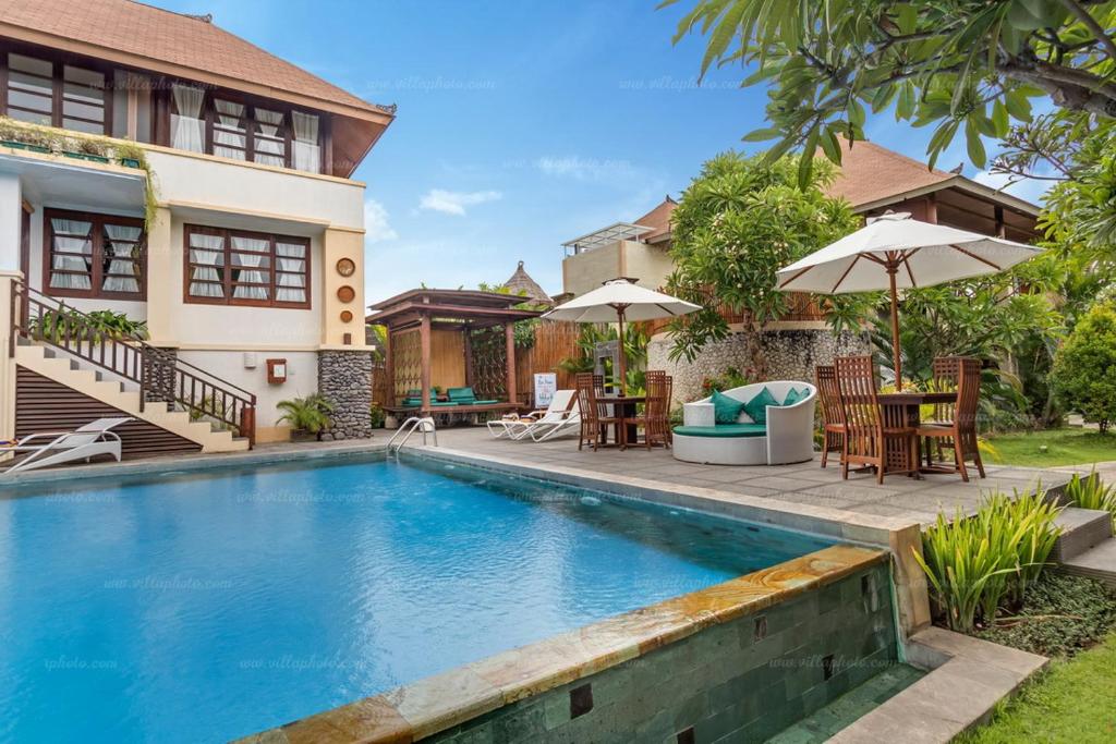a villa with a swimming pool in front of a house at Desamuda Village in Seminyak