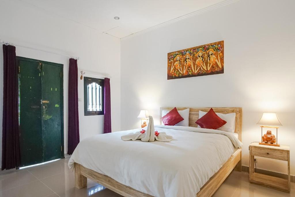 a bedroom with a large white bed with red pillows at Wayan Homestay Sanur in Sanur