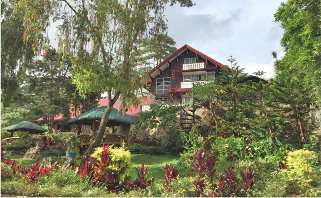 a house on top of a hill with a garden at Log Cabin Hotel - Safari Lodge Baguio in Baguio