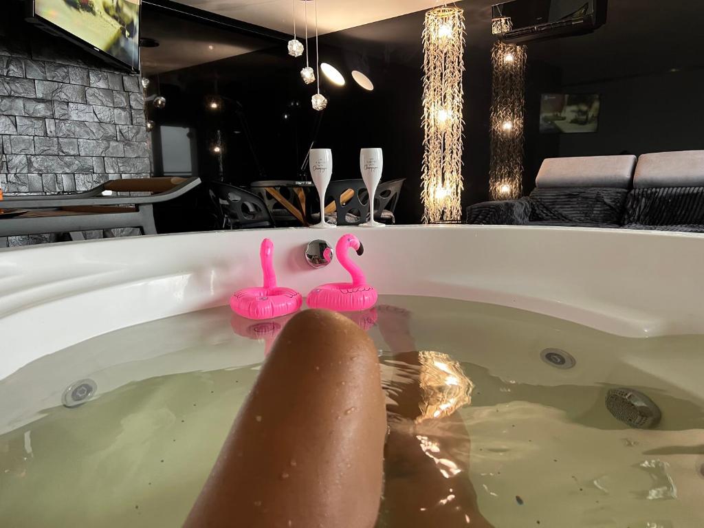 a bath tub filled with water with pink ducks in it at LUKSUSOWE Waikiki w Krainie Alicji in Ełk