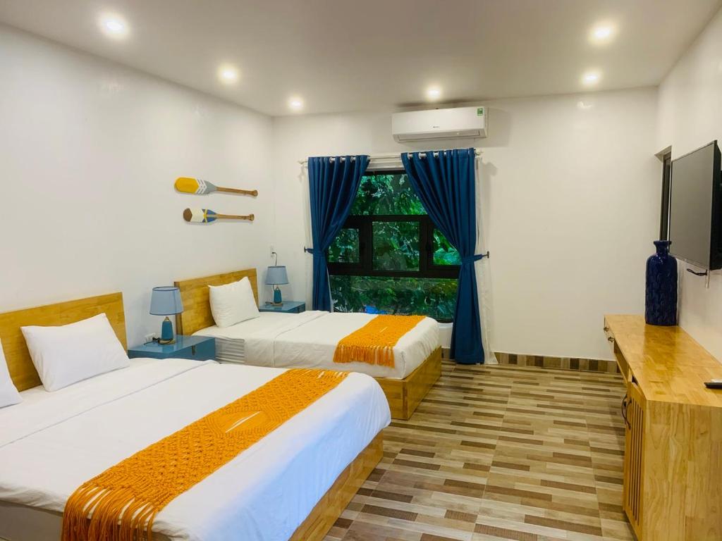 a bedroom with two beds and a tv and a window at SECRET GARDEN Hostel - WANDERNEST Cat Ba in Cat Ba