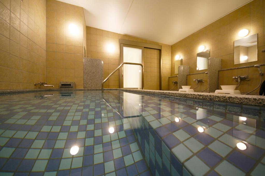 a bathroom with a swimming pool with two sinks and mirrors at Kuretake Inn Premium Shizuoka Annex in Shizuoka