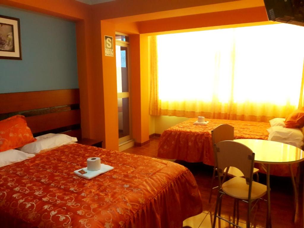a hotel room with two beds and a table and chairs at Tesoro Suite in Tacna