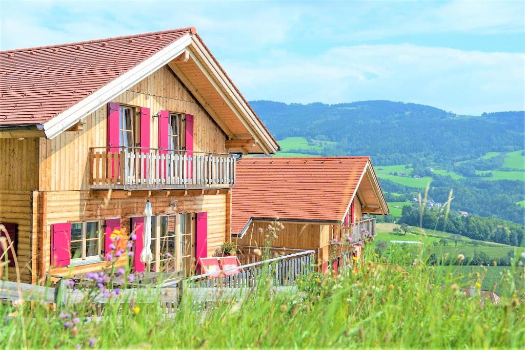 a wooden house with pink windows and a balcony at Ferienhaus mit Panoramaausblick und Sauna - 3 SZ in Pöllauberg