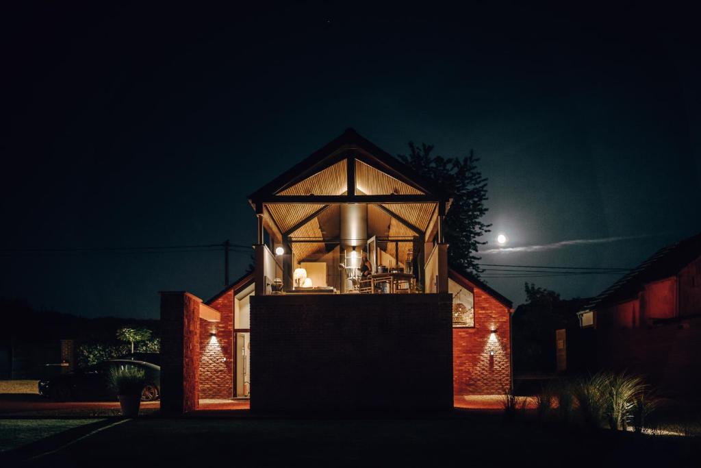 a glass house at night with the moon in the background at Comme chez Soye - Private Wellness in Soye