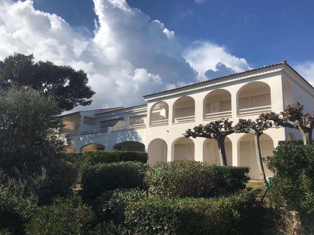 un edificio bianco con alberi di fronte di Coves Noves Nice apartment of 75 m2 10 minutes walk from the beach of Arenal d'en Castell a Es Mercadal