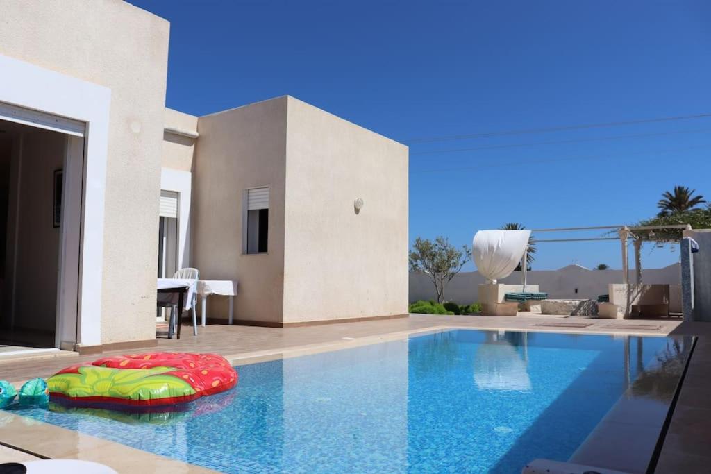 a swimming pool in front of a house at VILL LA REINE JERBA avec piscine in Djerba