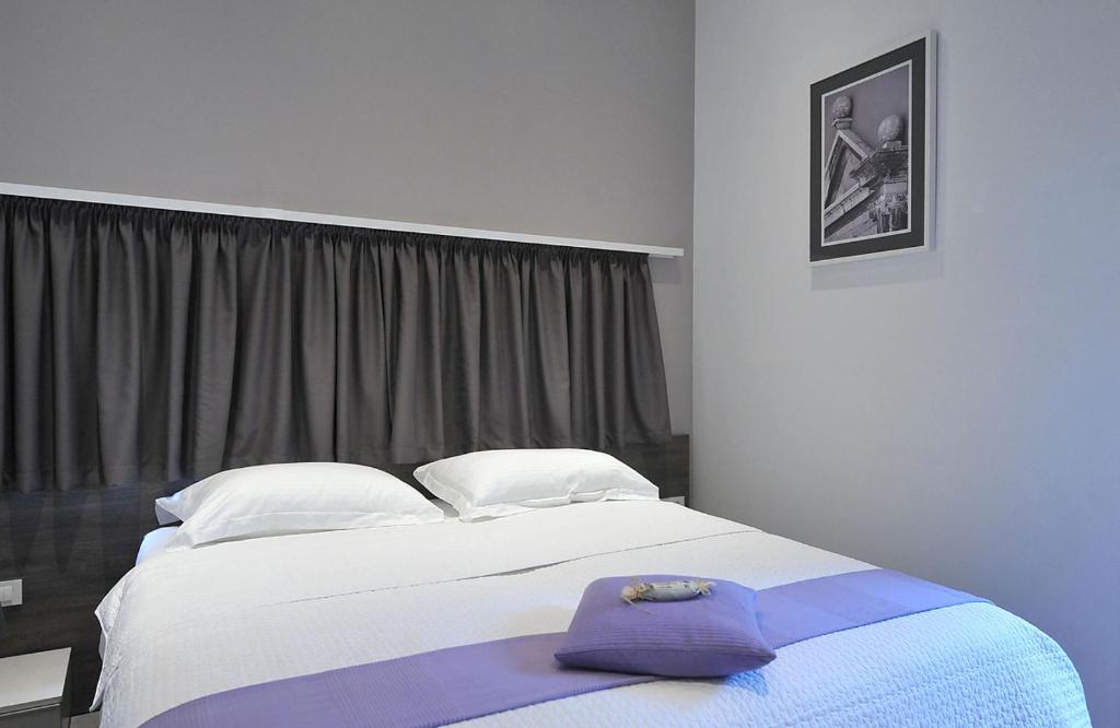 a bedroom with a large bed with a purple robe on it at Apartments & Rooms Lavandula Exclusive in Zadar