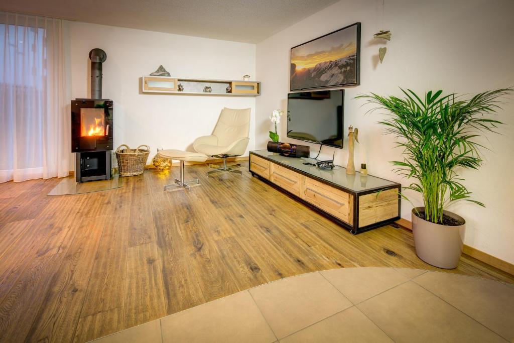 Matterhorngruss Apartments في زيرمات: غرفة معيشة مع أرضيات خشبية وتلفزيون وطاولة