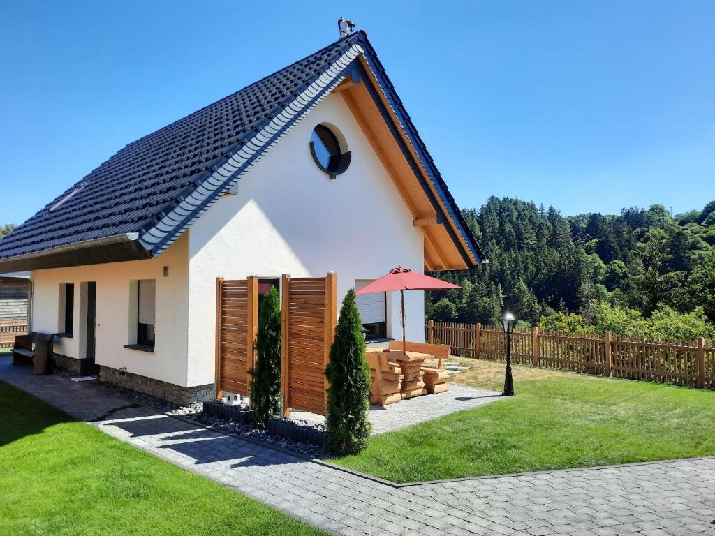 una pequeña casa blanca con valla y césped en Beim Schlafwandler, en Virneburg