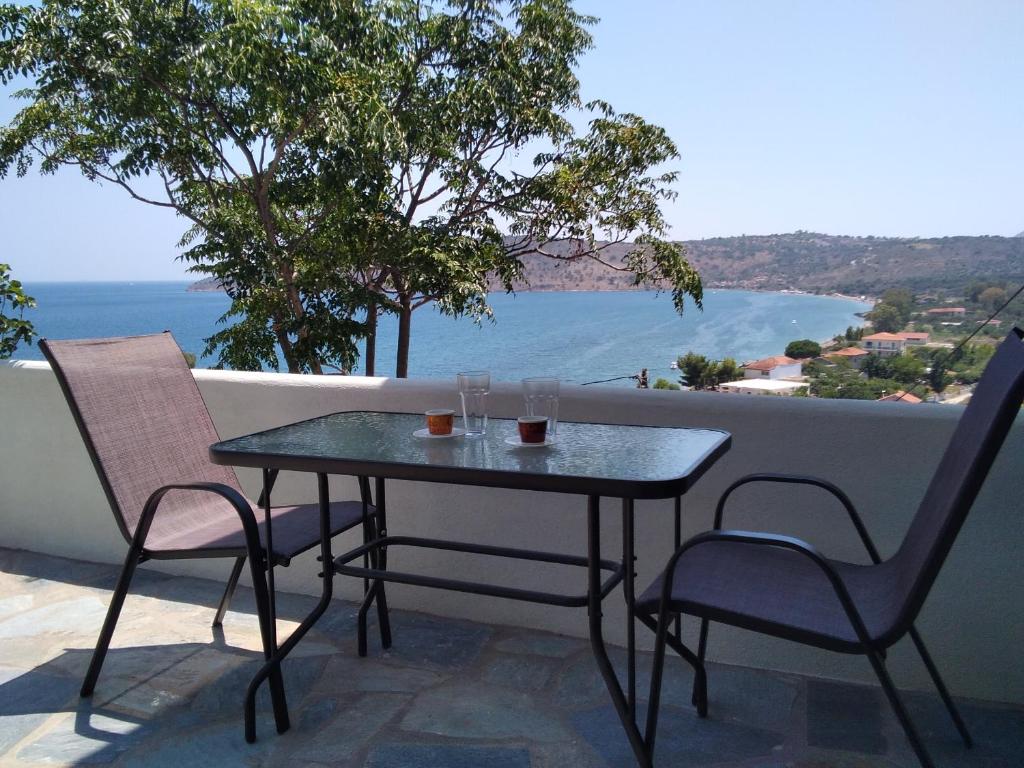 a table and chairs on a balcony with a view of the ocean at Κamares View (Αύρα) in Ayeranós