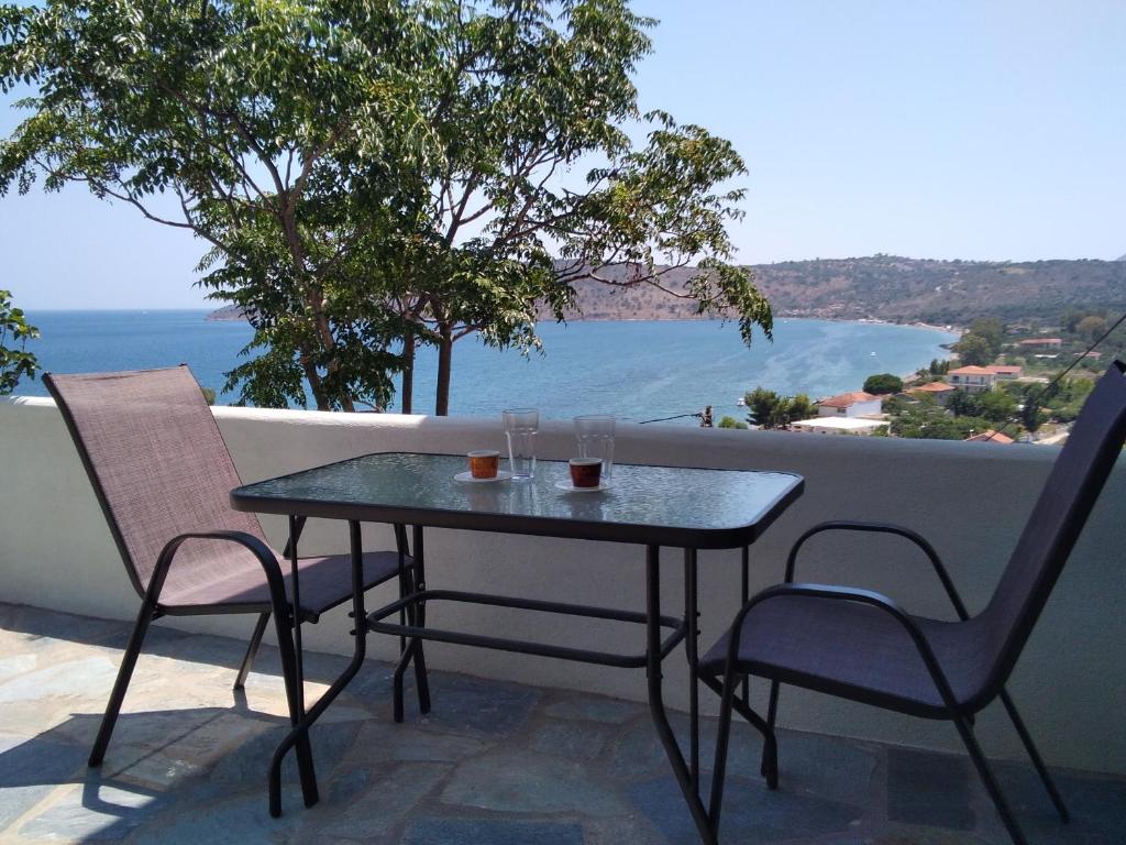 een tafel en stoelen op een balkon met uitzicht op de oceaan bij Κamares View (Αύρα) in Ayeranós
