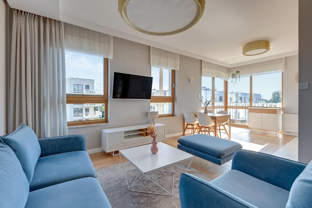 un salon avec des canapés bleus et une télévision dans l'établissement Downtown Apartments Seaside Mila Baltica - Sauna, Gym & Parking, à Gdańsk