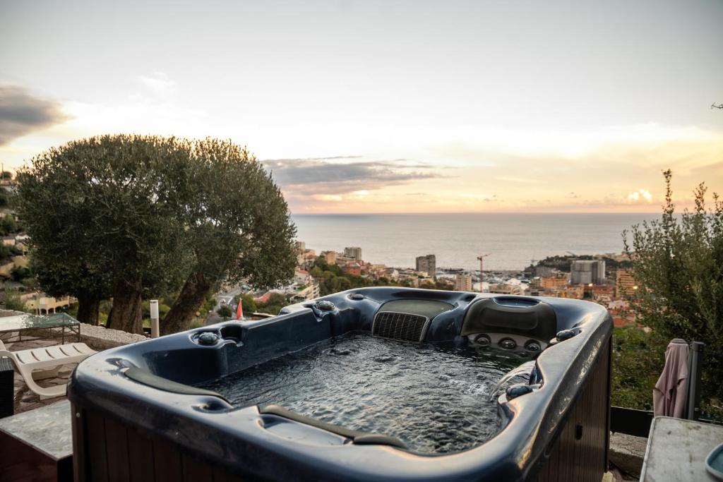 uma banheira de hidromassagem numa varanda com vista para o oceano em Le petit jardin exotique em Beausoleil