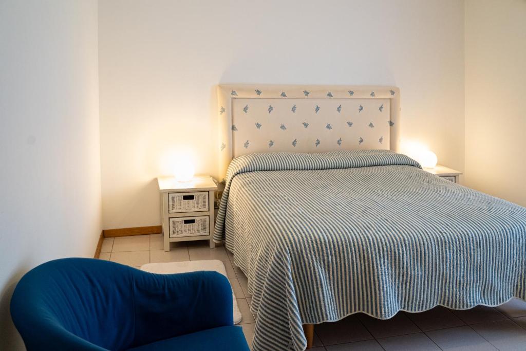 - une chambre avec un lit et une chaise bleue dans l'établissement Elegant apartment in residence with pool, à Acireale