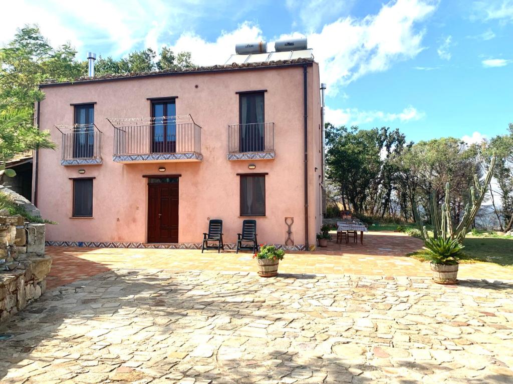 ein großes rosafarbenes Haus mit Stühlen davor in der Unterkunft Agriturismo San Pietro in Gangi