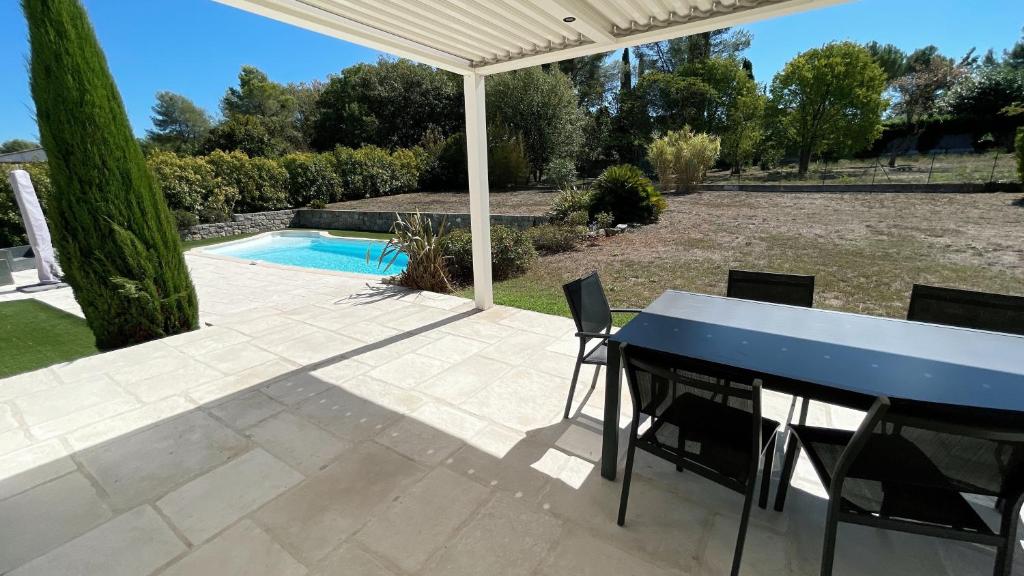 um pátio com uma mesa e cadeiras azuis e uma piscina em Villa des Chardonnerets em Mougins