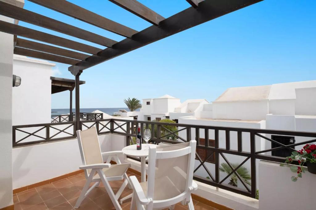 uma varanda com cadeiras brancas e vista para o oceano em Casa Sol y Playa em Playa Honda