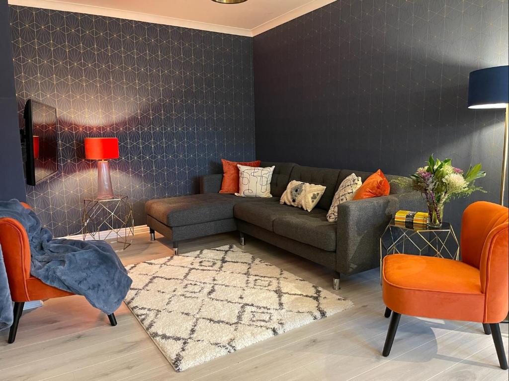 sala de estar con sofá gris y sillas naranjas en East Walls Apartment en Chichester