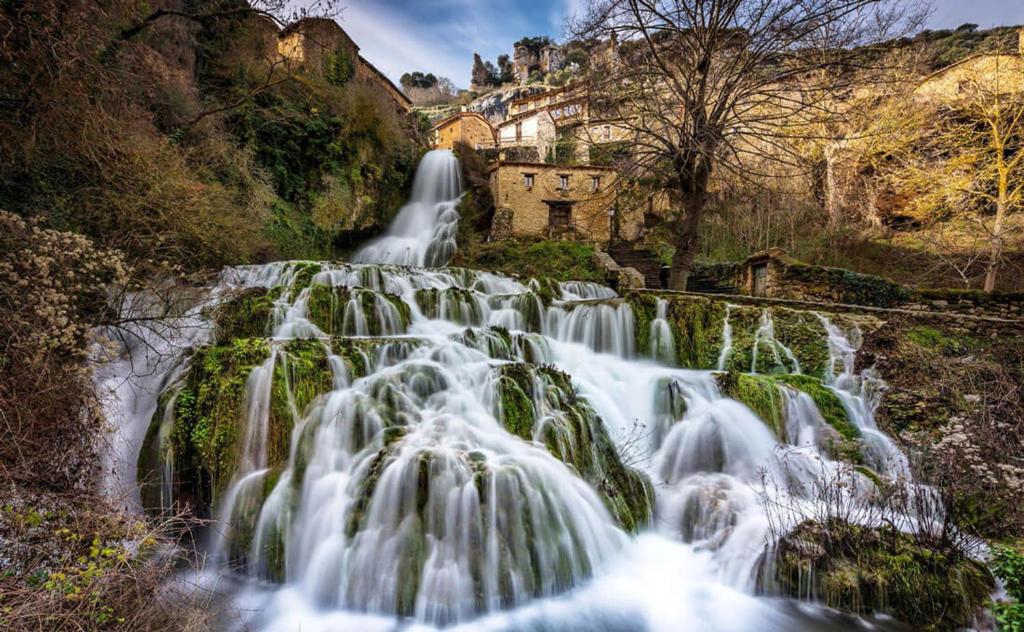 einem Wasserfall an der Seite eines Berges in der Unterkunft El Salto del Agua Auténtico El Molino de la Cascada Orbaneja in Orbaneja del Castillo