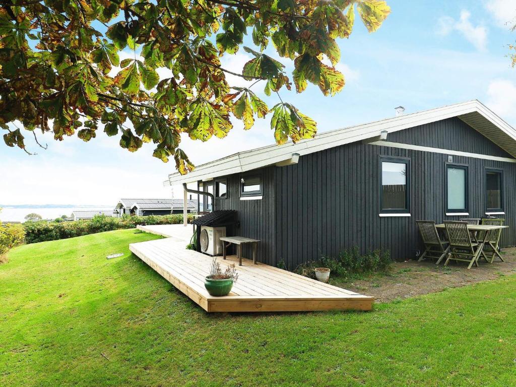 Helnæs By的住宿－6 person holiday home in Ebberup，庭院里带木甲板的黑色房子