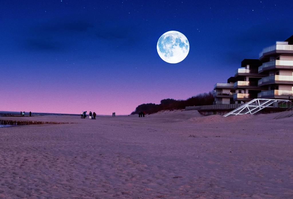 a full moon rising over a beach at night at GARDENIA SUPERIOR apartament 33 in Dziwnów