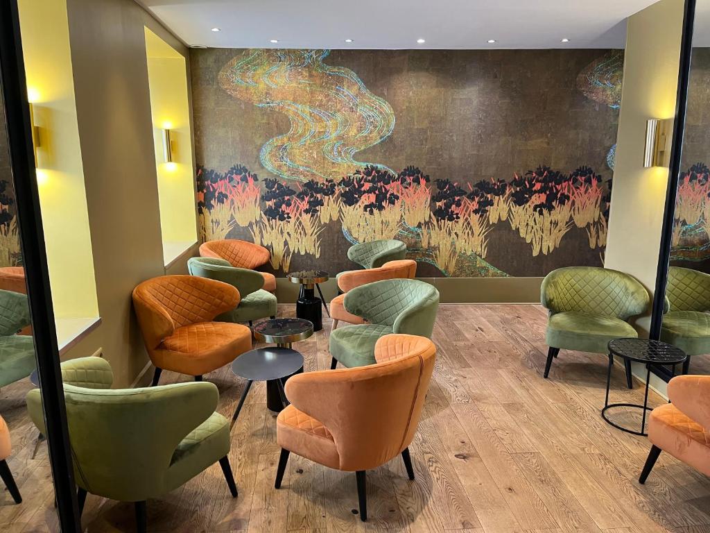 uma sala de espera com cadeiras coloridas e um quadro em 55 Hôtel Montparnasse em Paris