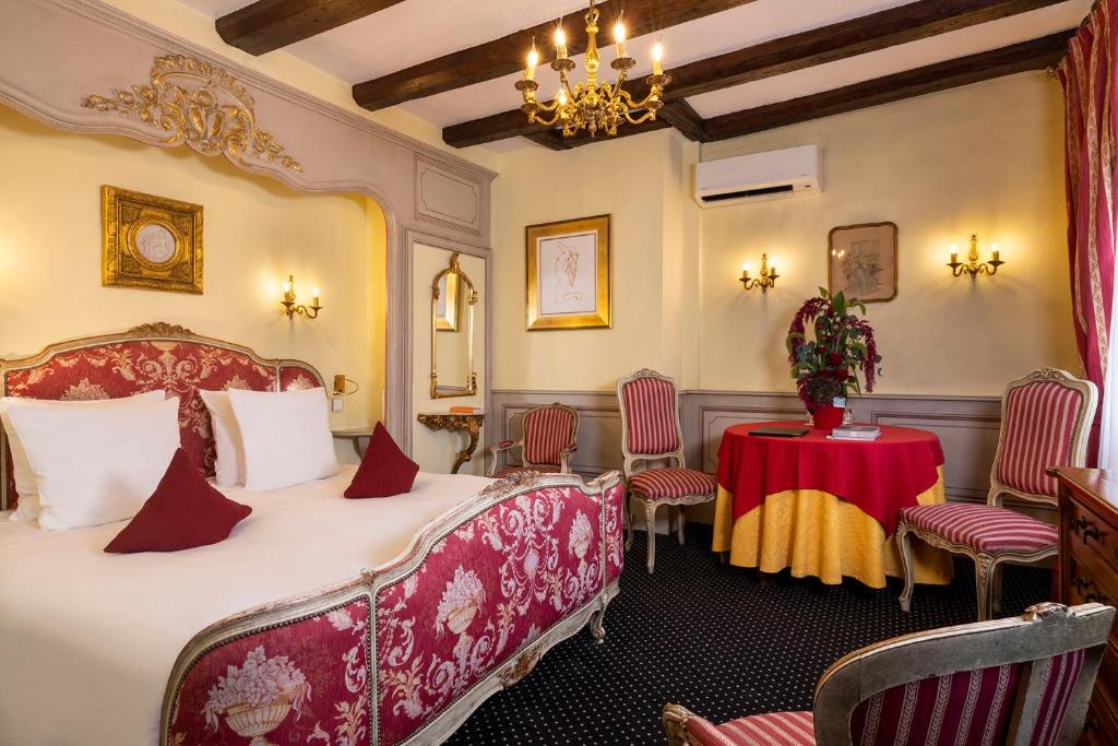 a bedroom with a bed and a table and chairs at Hotel Restaurant Le Maréchal - Teritoria in Colmar
