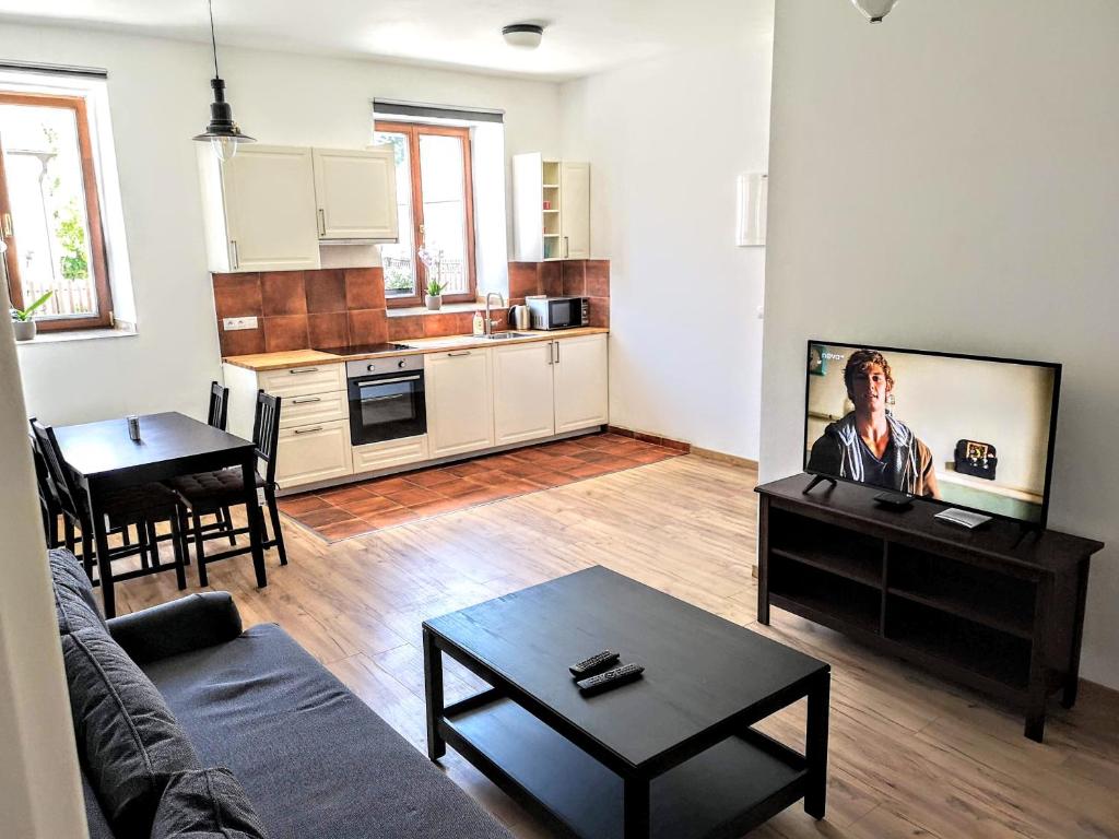 ein Wohnzimmer mit einem Sofa und einem Tisch sowie eine Küche in der Unterkunft Apartmány Na hrnčírně in Suchdol nad Lužnicí