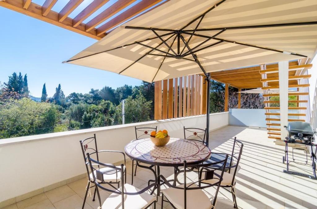 une terrasse avec une table, des chaises et un parasol dans l'établissement Apartment Lula, à Orašac