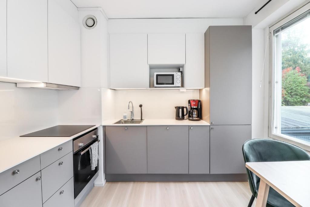 eine Küche mit weißen Schränken und einem Fenster in der Unterkunft Cosy flat with good transport connections in Vantaa