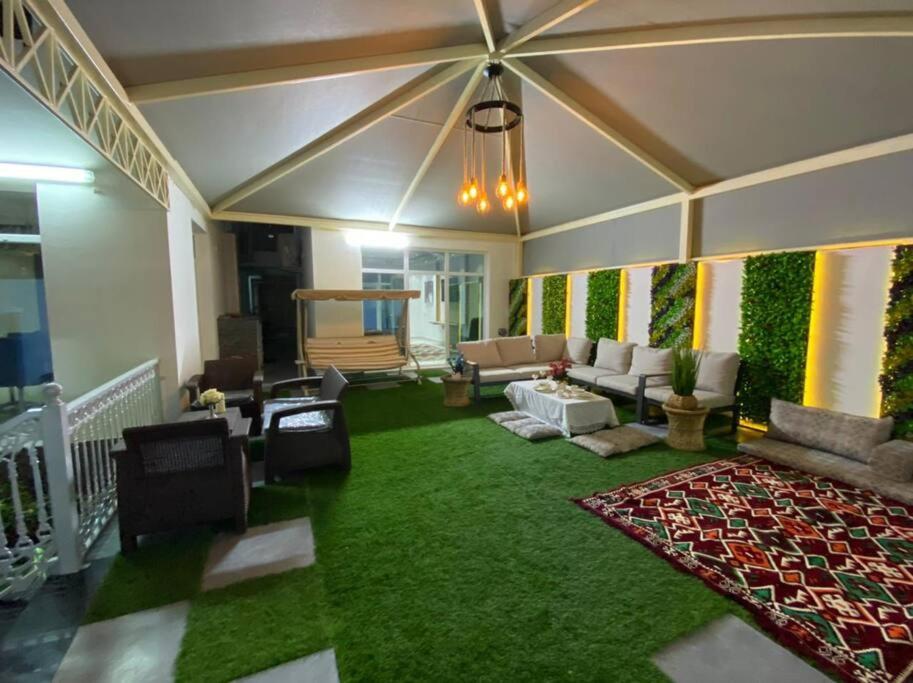 Al Aryam Villa في Mawāliḩ: غرفة معيشة مع أريكة وسجادة خضراء