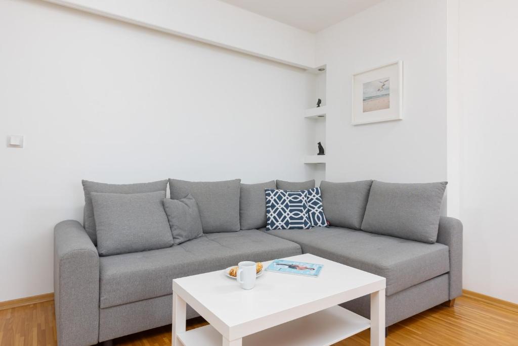 a living room with a gray couch and a white table at Spacious Apartment Pałac Jana III Wilanów by Renters in Warsaw