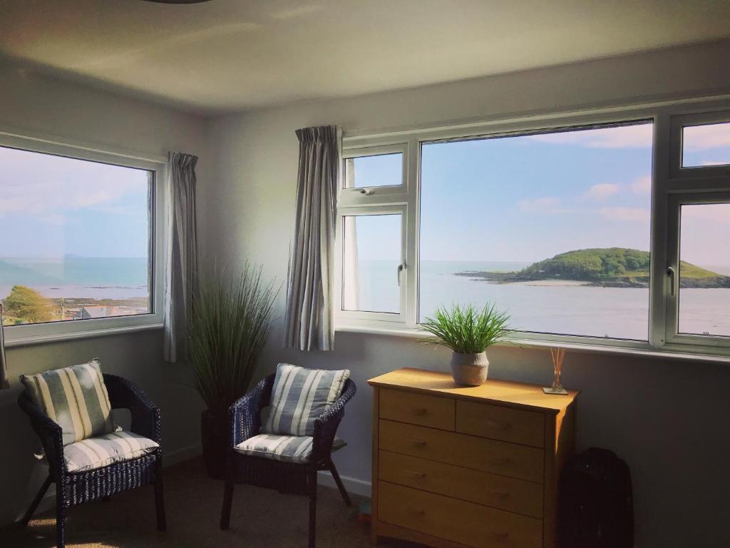 sala de estar con 2 sillas y 2 ventanas en Sea Spirit - Sweeping Sea Views first floor spacious modern apartment in Looe- with FREE parking!, en Looe