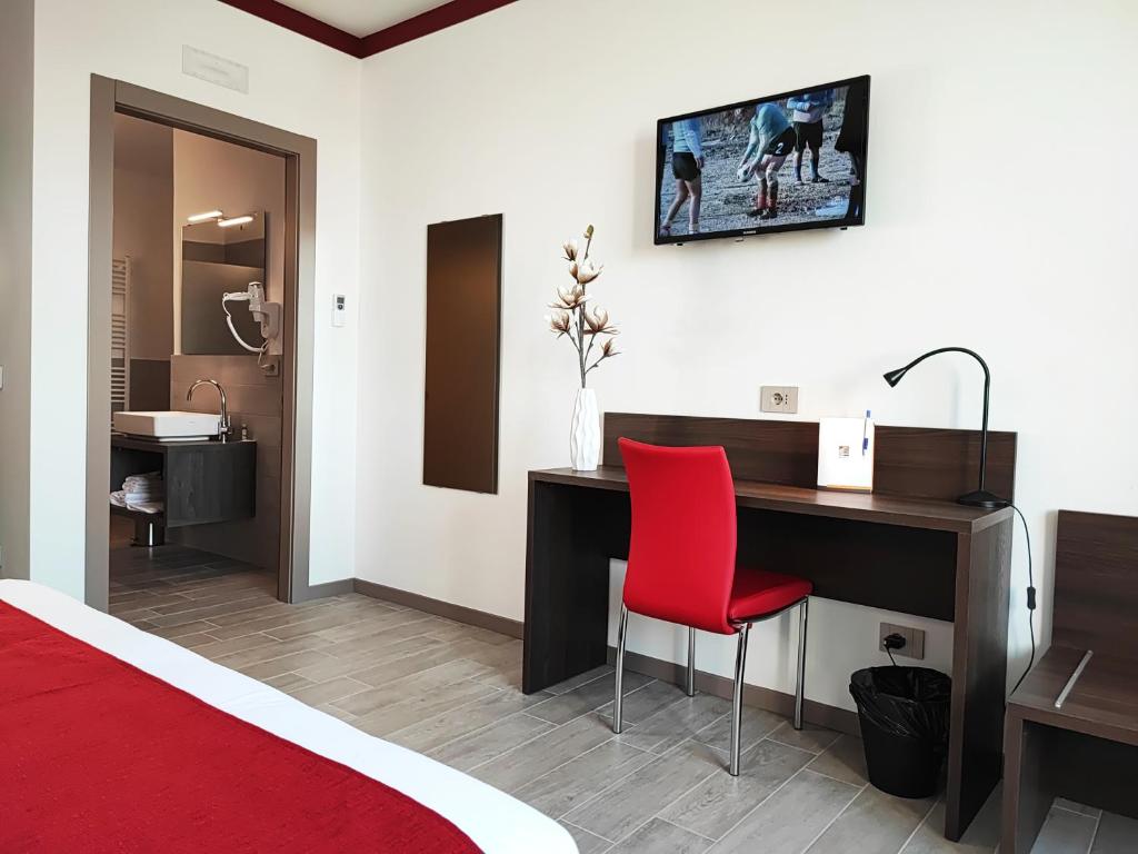 a bedroom with a desk and a red chair at Suites Direzionale Carpi in Carpi