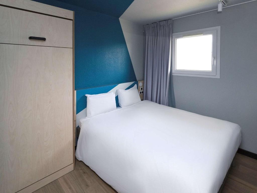 Un dormitorio con una gran cama blanca y una ventana en ibis Budget La Teste Bassin d'Arcachon, en La Teste-de-Buch