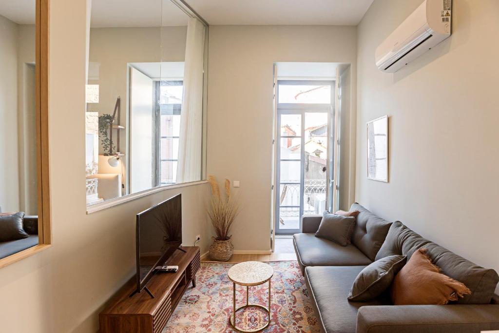 een woonkamer met een bank en een televisie bij 31 Janeiro 157 - Stylish 1BR w/ AC & Balcony by LovelyStay in Porto