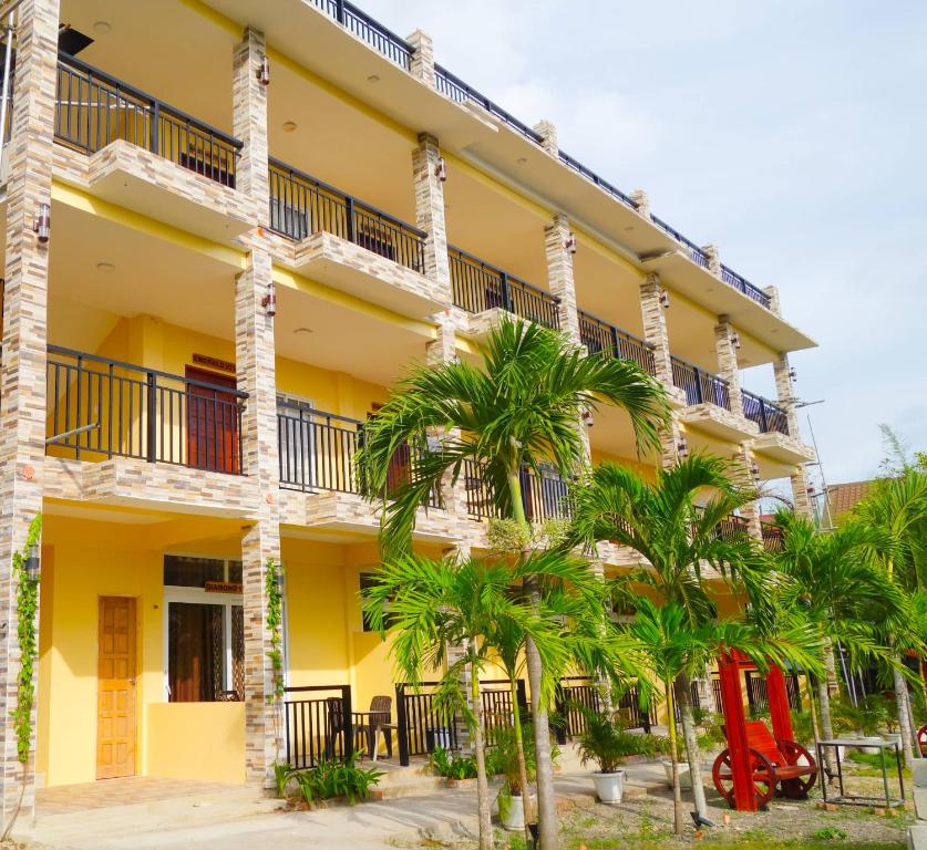 um edifício amarelo com palmeiras em frente em Gem's Paradise Resort em Cebu