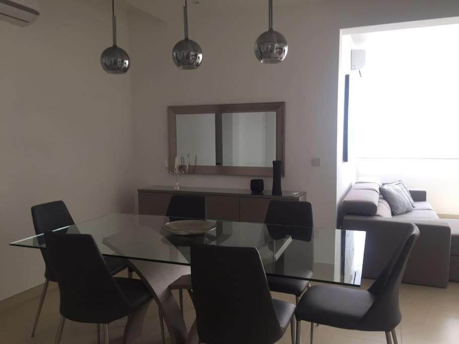a dining room with a glass table and chairs at THE ONE - 4 Bedroom St Julian’s in St. Julianʼs