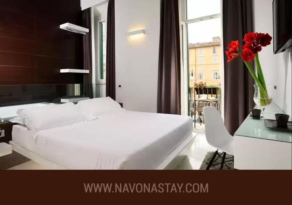 una camera da letto con un letto bianco e un vaso di fiori rossi di Navona Stay a Roma