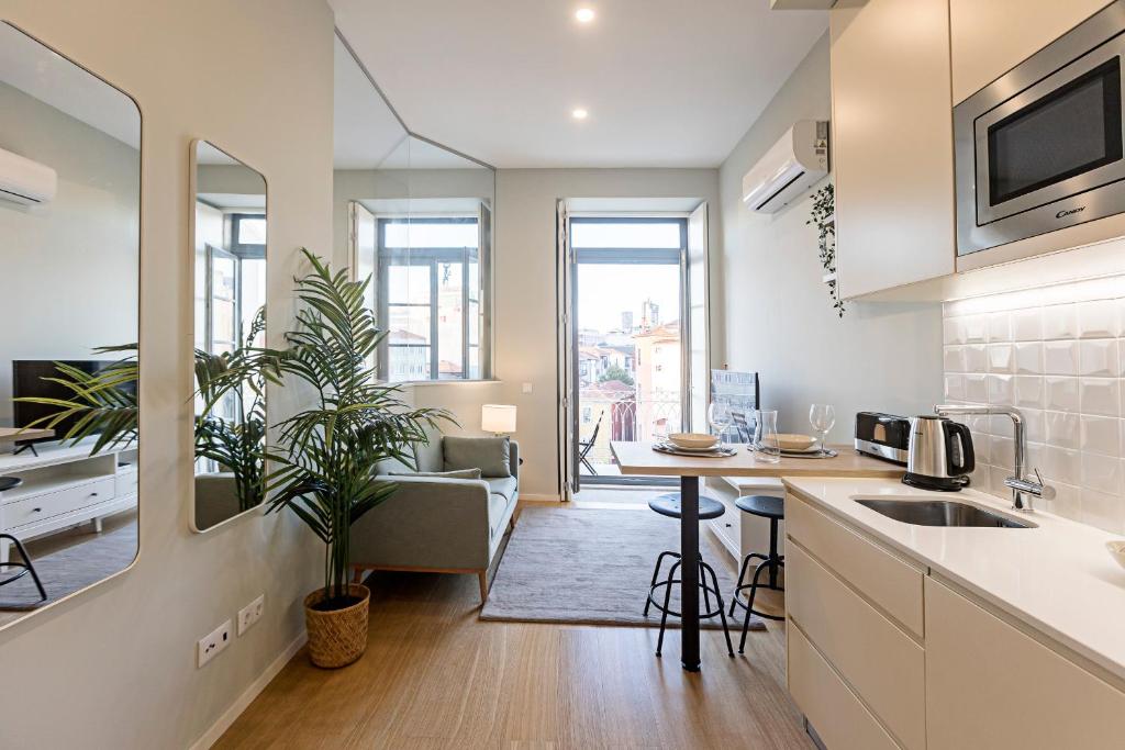 een keuken en een woonkamer met een tafel en een bank bij 31 Janeiro 157 - Delightful 1BR Flat w/ AC & Balcony by LovelyStay in Porto